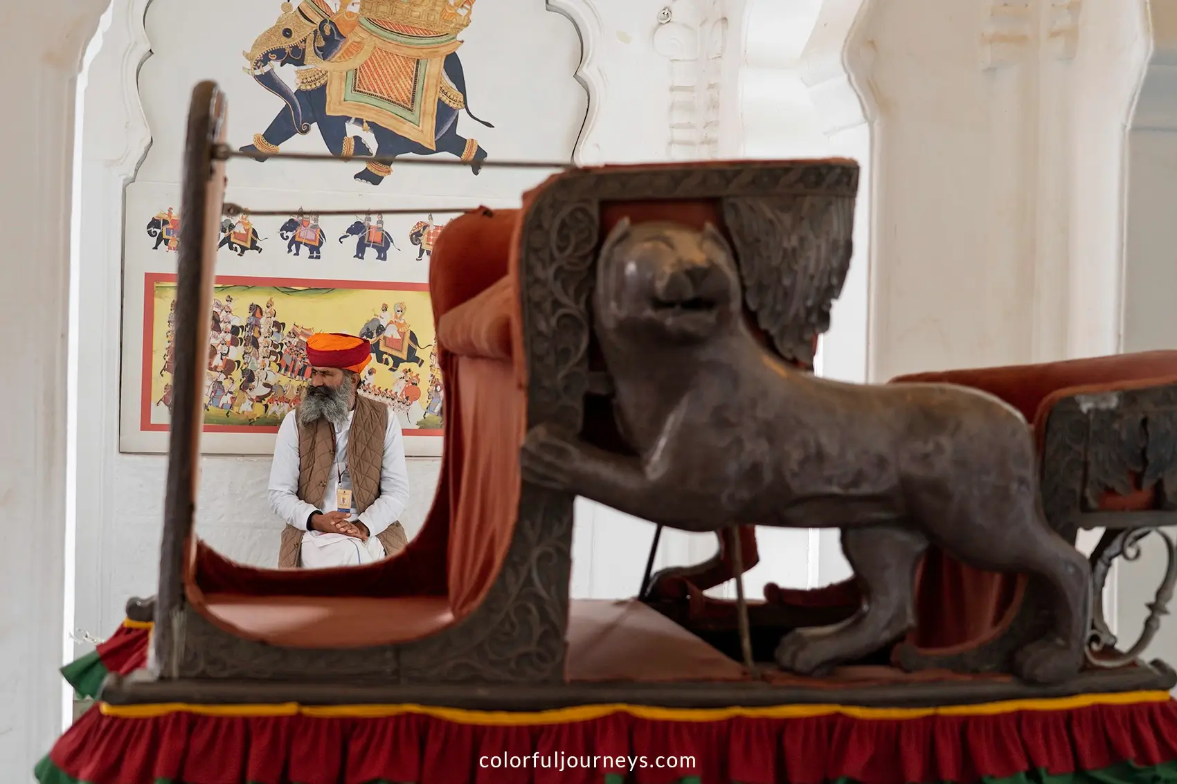 A guard sits next to a Howdah at Mehrangarh Fort in Jodhpur, India