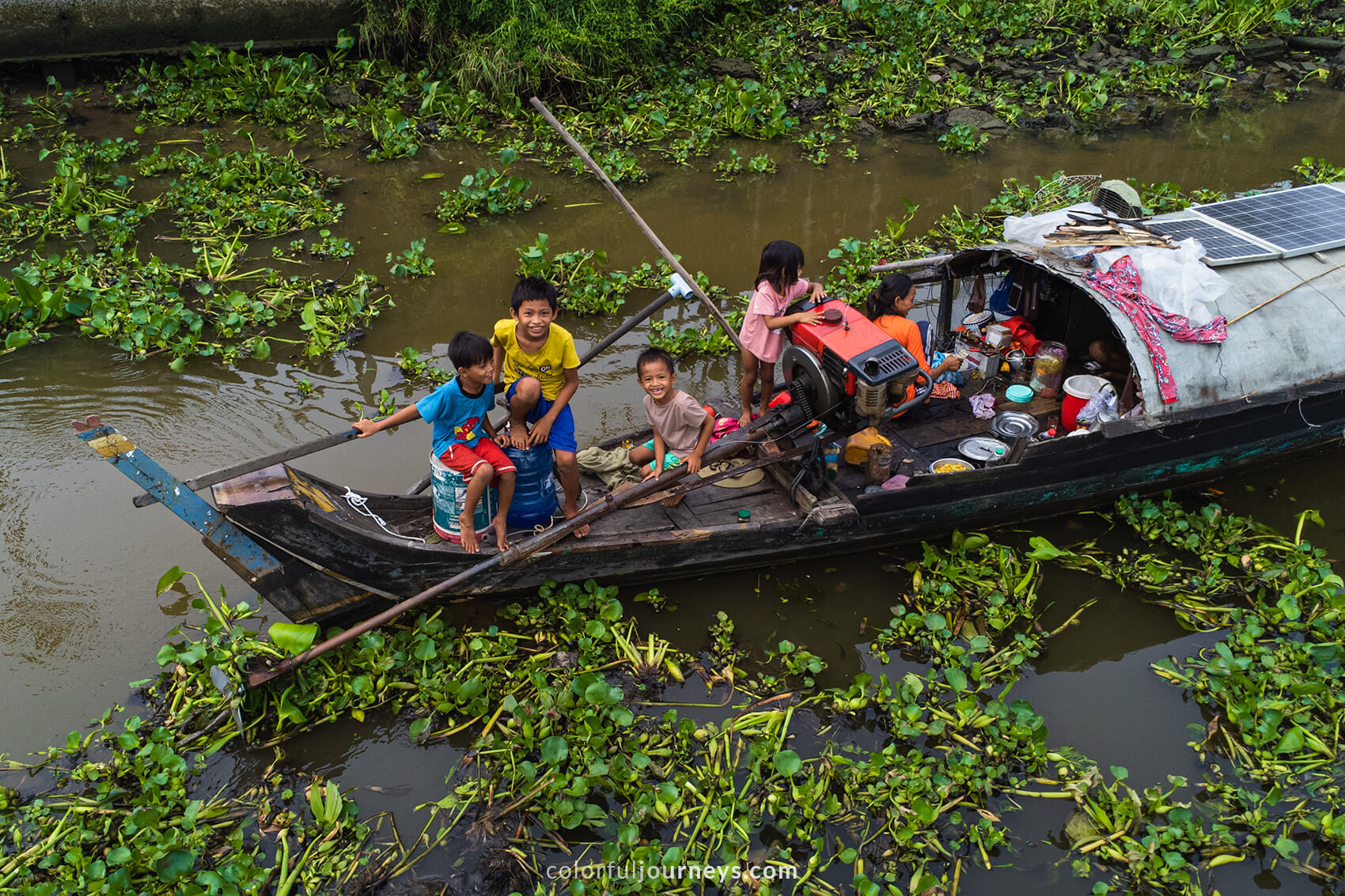 A family of seven lives together on a small boat, the kids laugh at the camera.