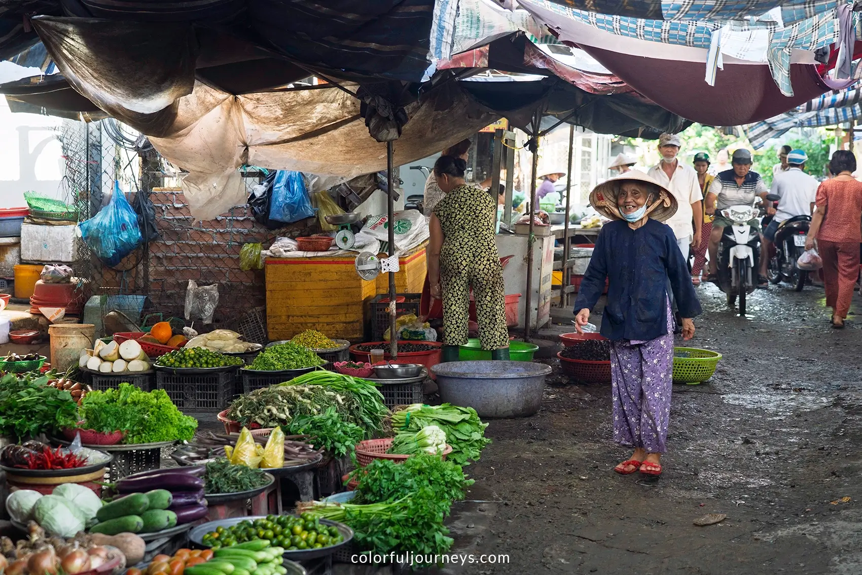 A woman wearing a non la strolls on a market in Vietnam