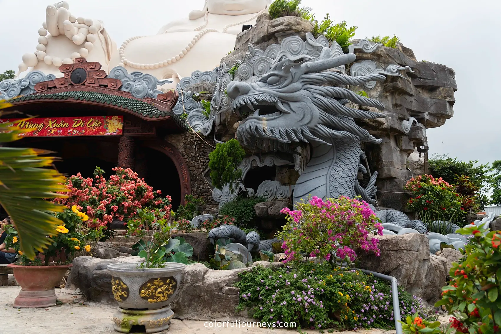 A statue of a dragon in front of a sitting Buddha statue. 