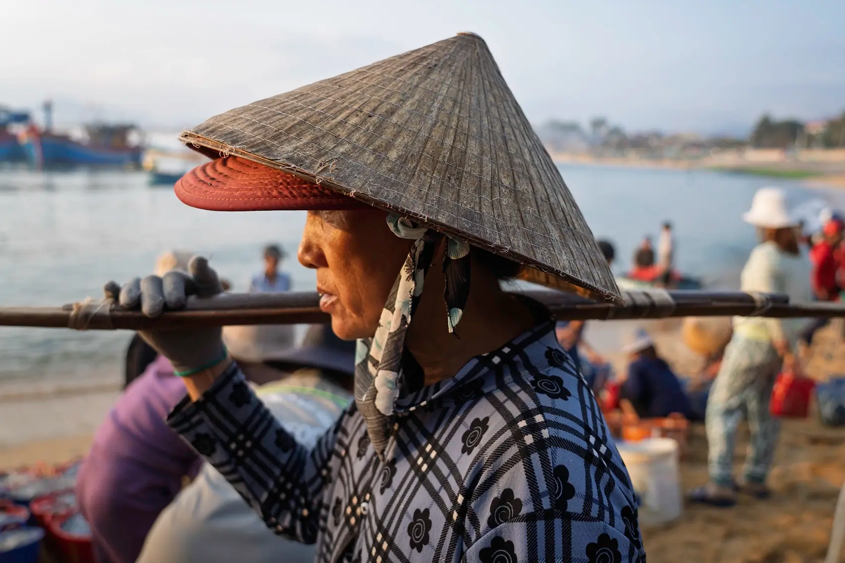 A woman wearing a conical hat on a beach in Vietnam