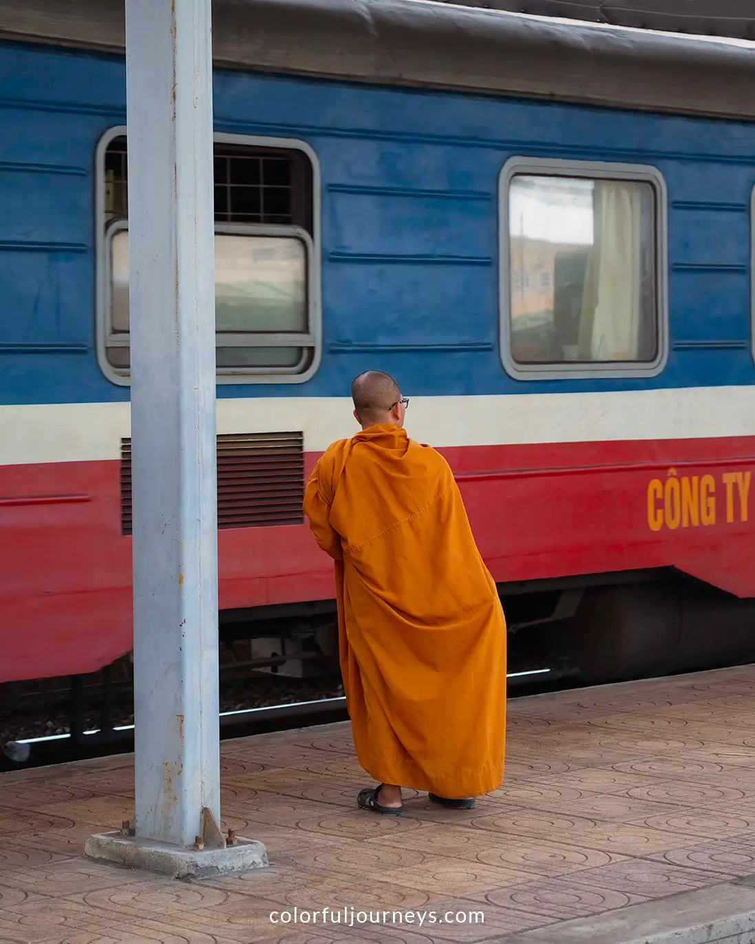 A monk wearing an orange robe waits for the train in Nha Trang, Vietnam