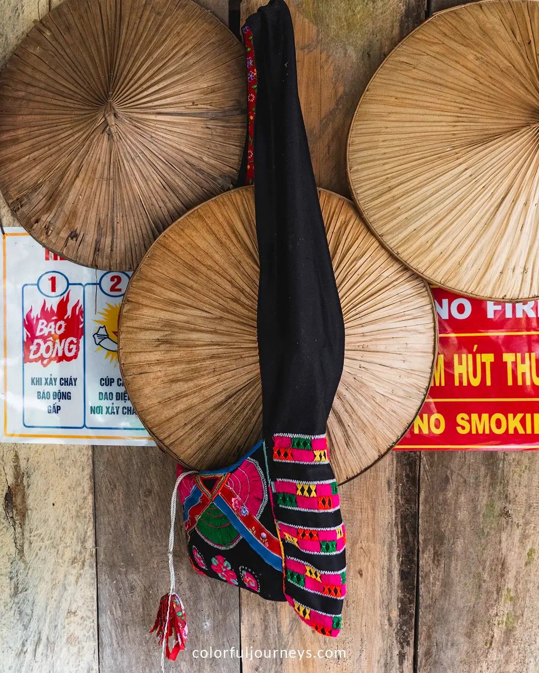 Conical hats an a bag from the Tay people hang on a wooden wall. 