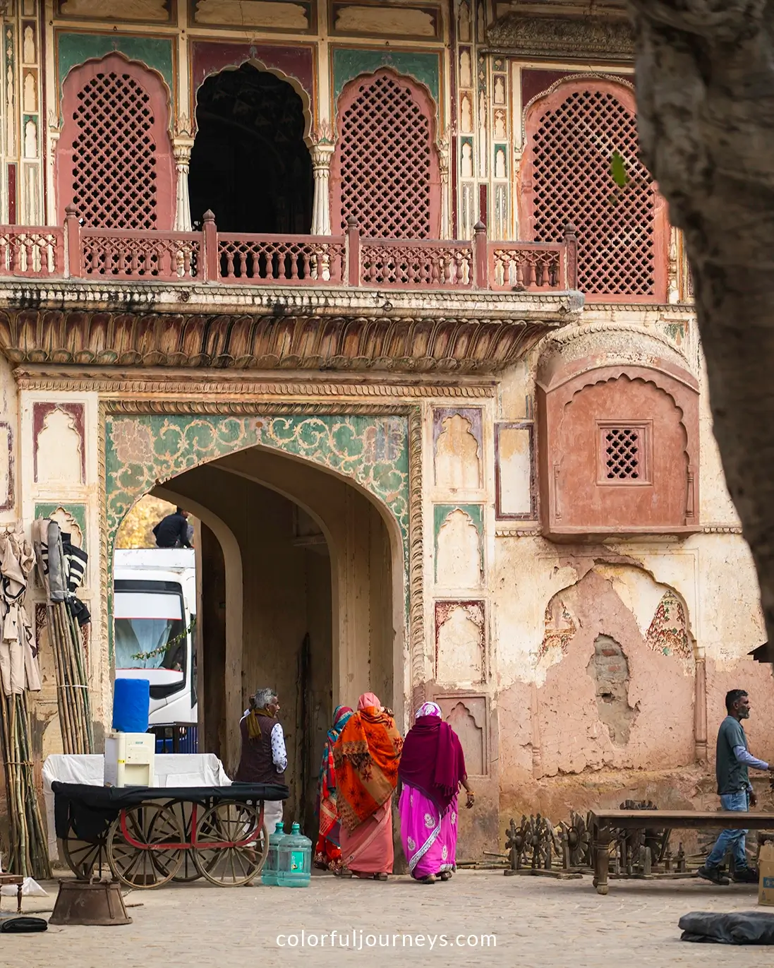 Women in colorful sarees walk underneath a gate at the Monkey Temple in Jaipur, India
