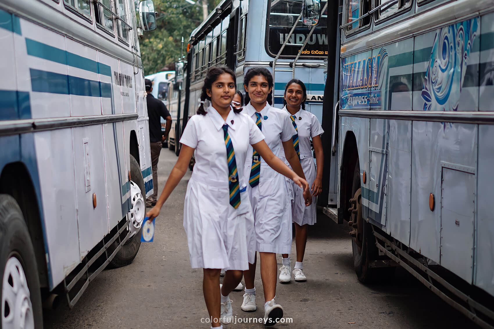 A group of school girls walks in between busses in Kandy, Sri Lanka. 