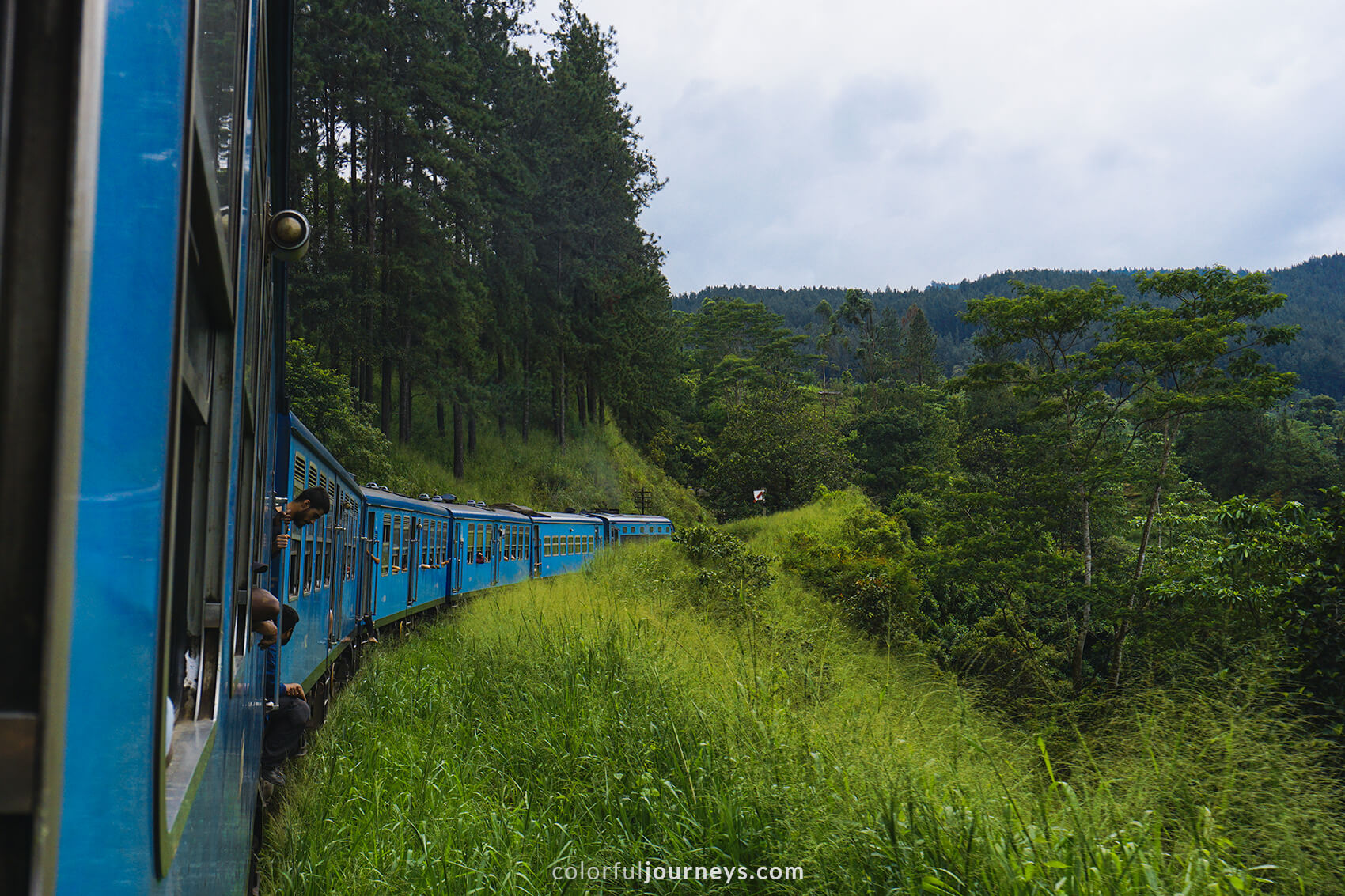 A blue train passes through green mountains in Ella, Sri Lanka