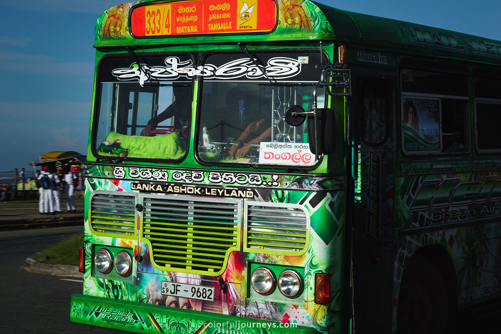 A green bus covered in colorful paintings.