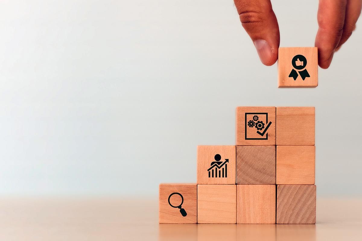 Photo of hand placing a building block at the top of a pyramid.