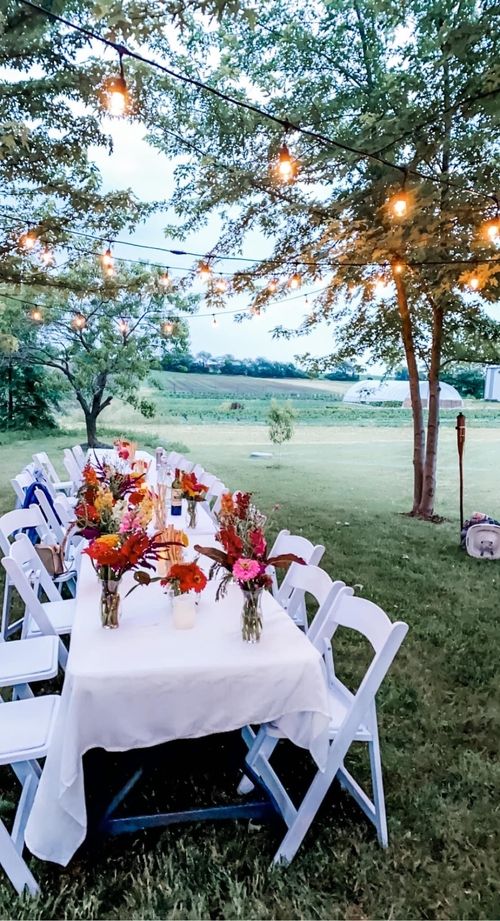 a long table with flower bouquets under a canopy of trees
