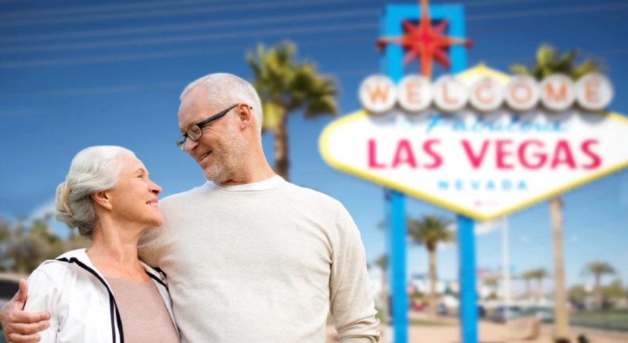 happy senior couple hugging over welcome to fabulous las vegas sign
