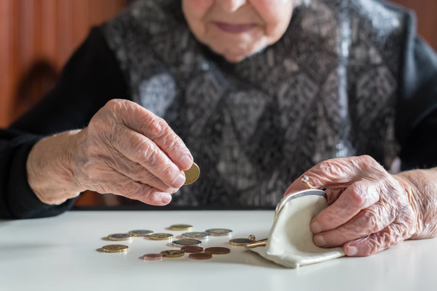 Elderly person counting coins and holding coin purse