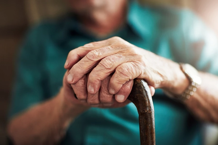 Close up of old man’s hands in cane