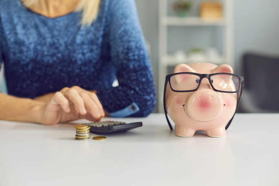 Woman with calculator next to piggy bank