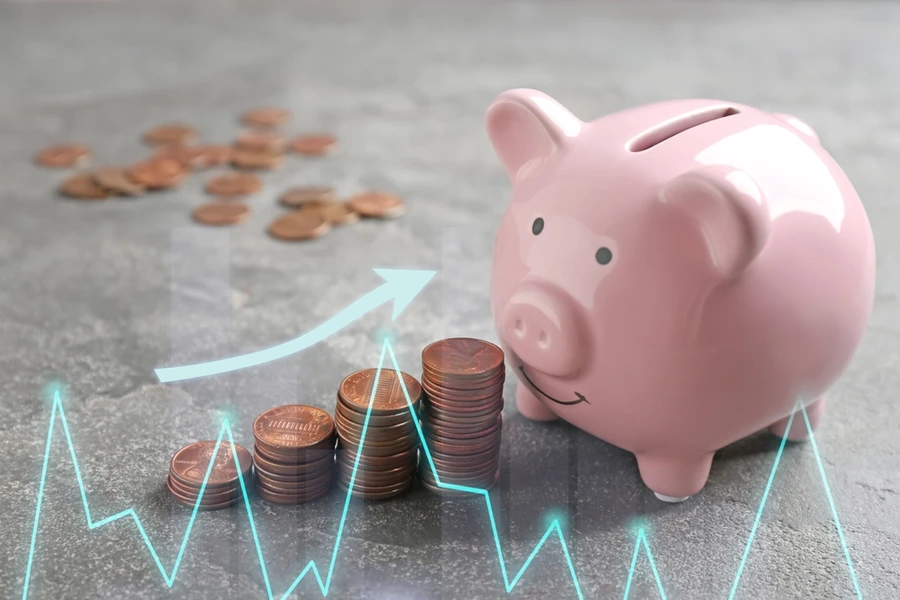 Piggy bank and coins on grey table
