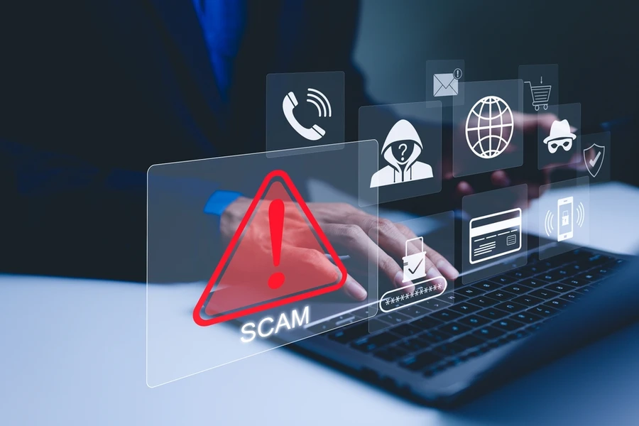 A person using laptop, warning sign for scams with icons representing online threats, phishing, and cybersecurity