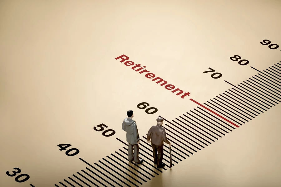 retirement age scale on background with little dolls of elderly businessman and young man