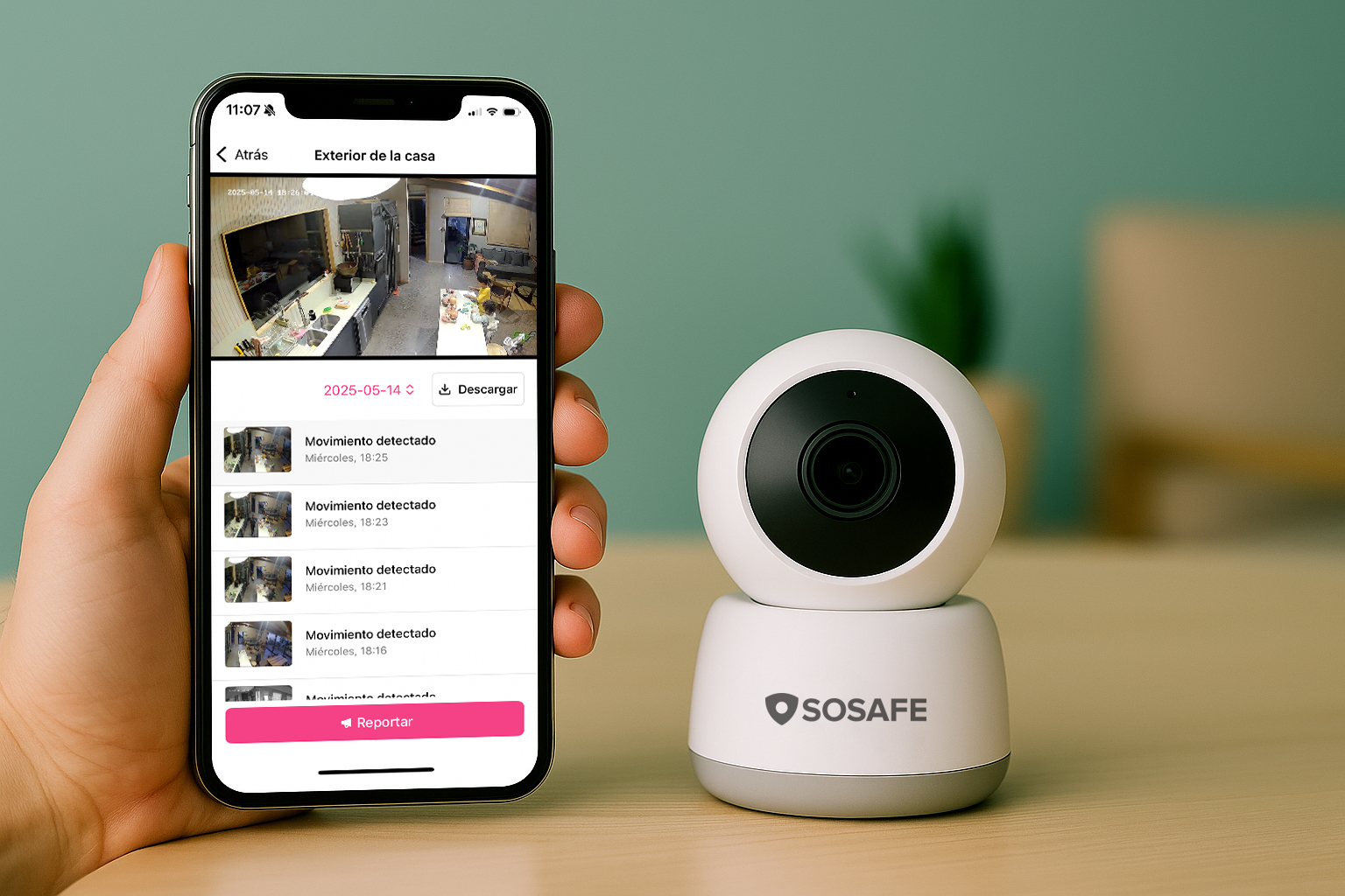 Una mano sostiene un smartphone en el que se ven las alertas de detección de movimiento de una aplicación de cámaras de seguridad domésticas, junto a una cámara de seguridad SOSAFE blanca colocada sobre una superficie de madera.