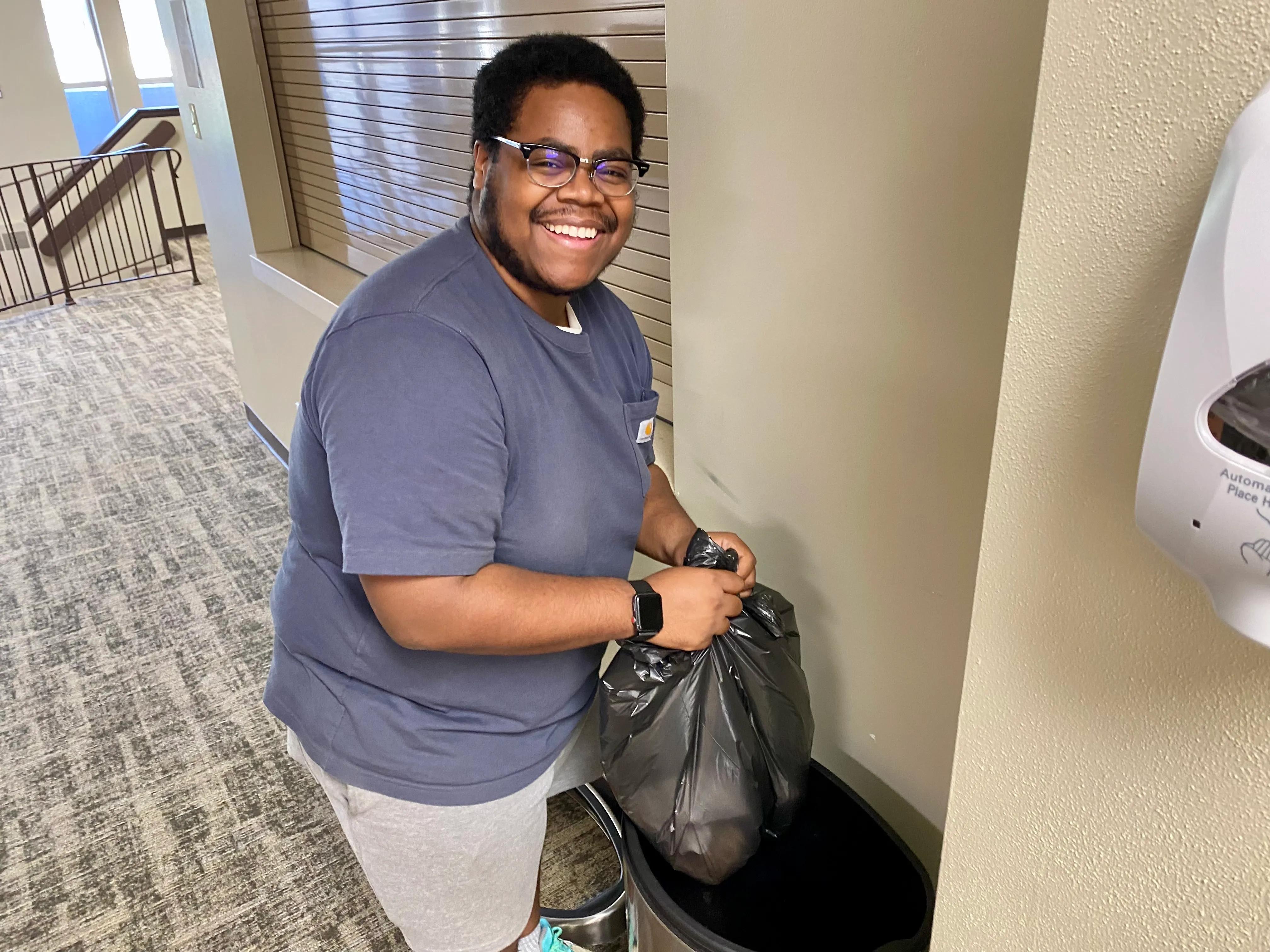 An image showcasing an individual with a smile on their face while properly disposing of garbage in a bin at Reach Church.