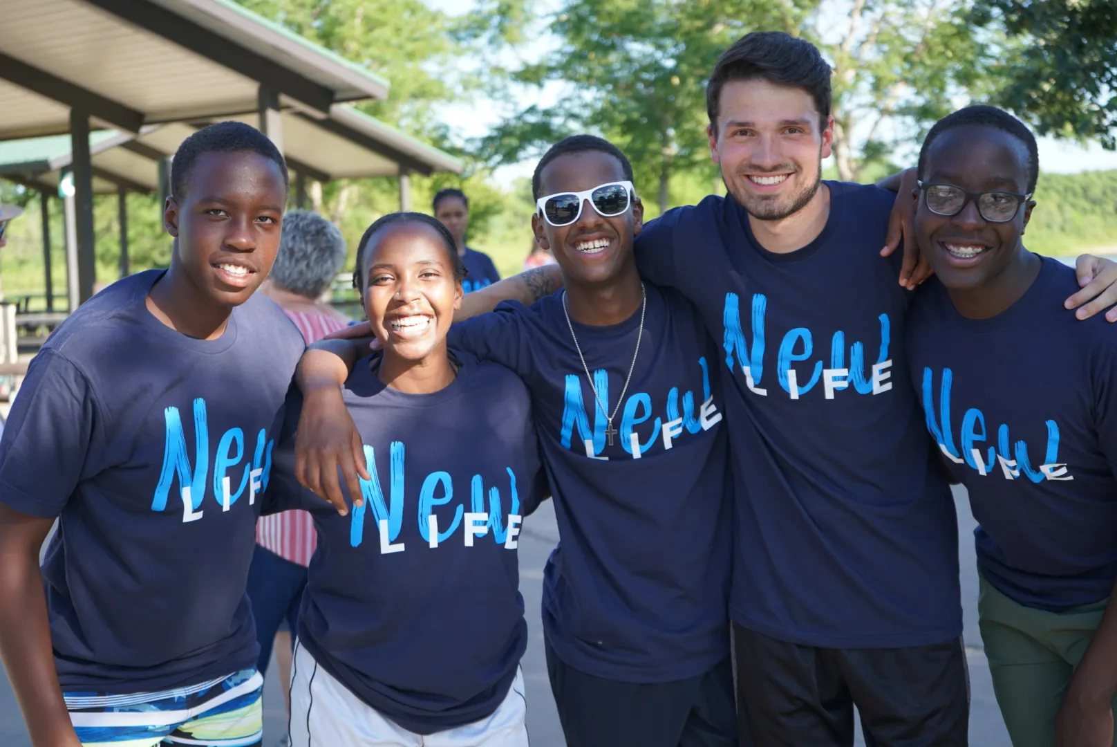 Image of a baptism event at Reach Church, featuring a group of happy young people wearing 'New Life' t-shirts.