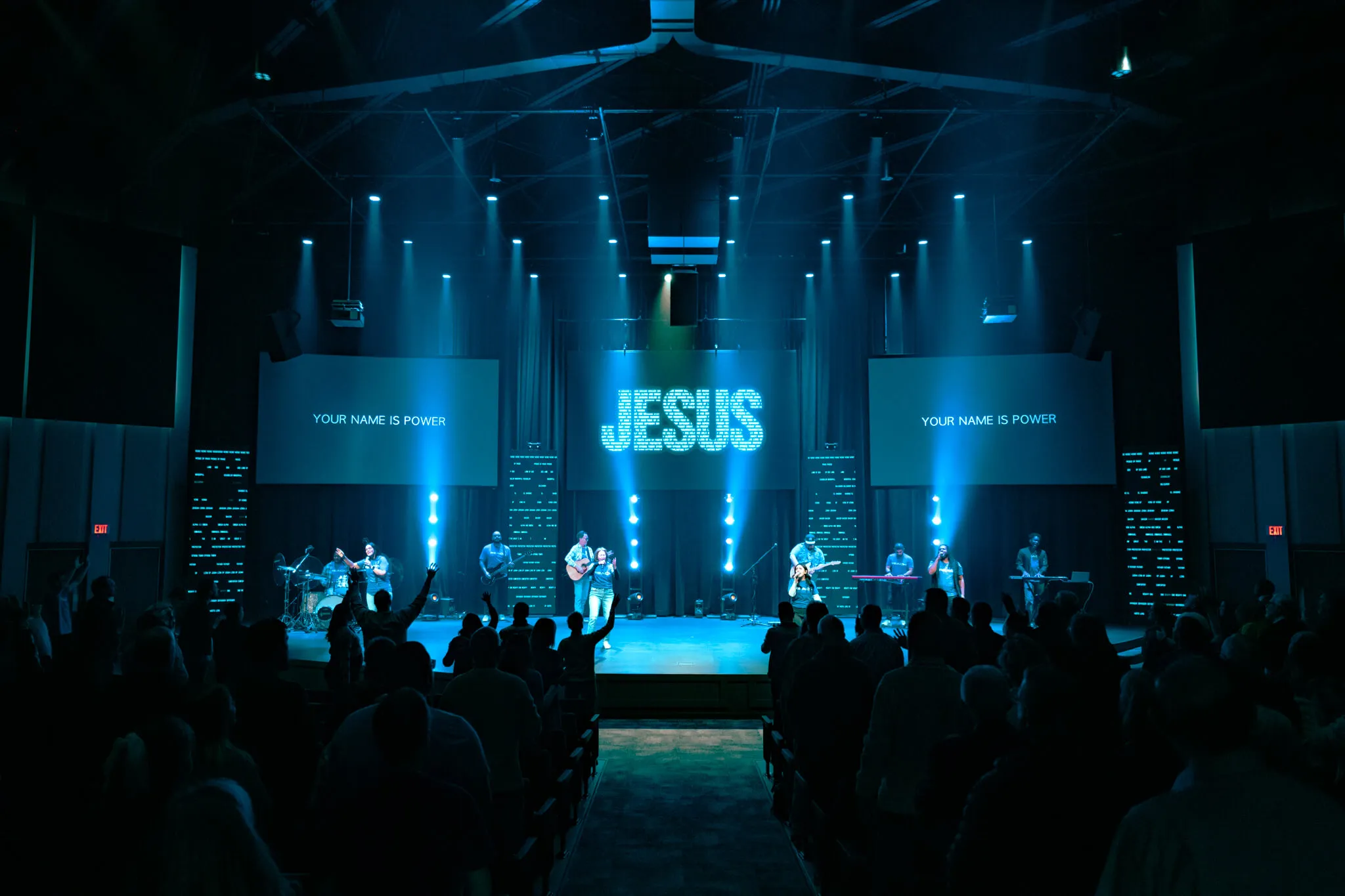 People listening and raising their hands during live worship at Reach Church