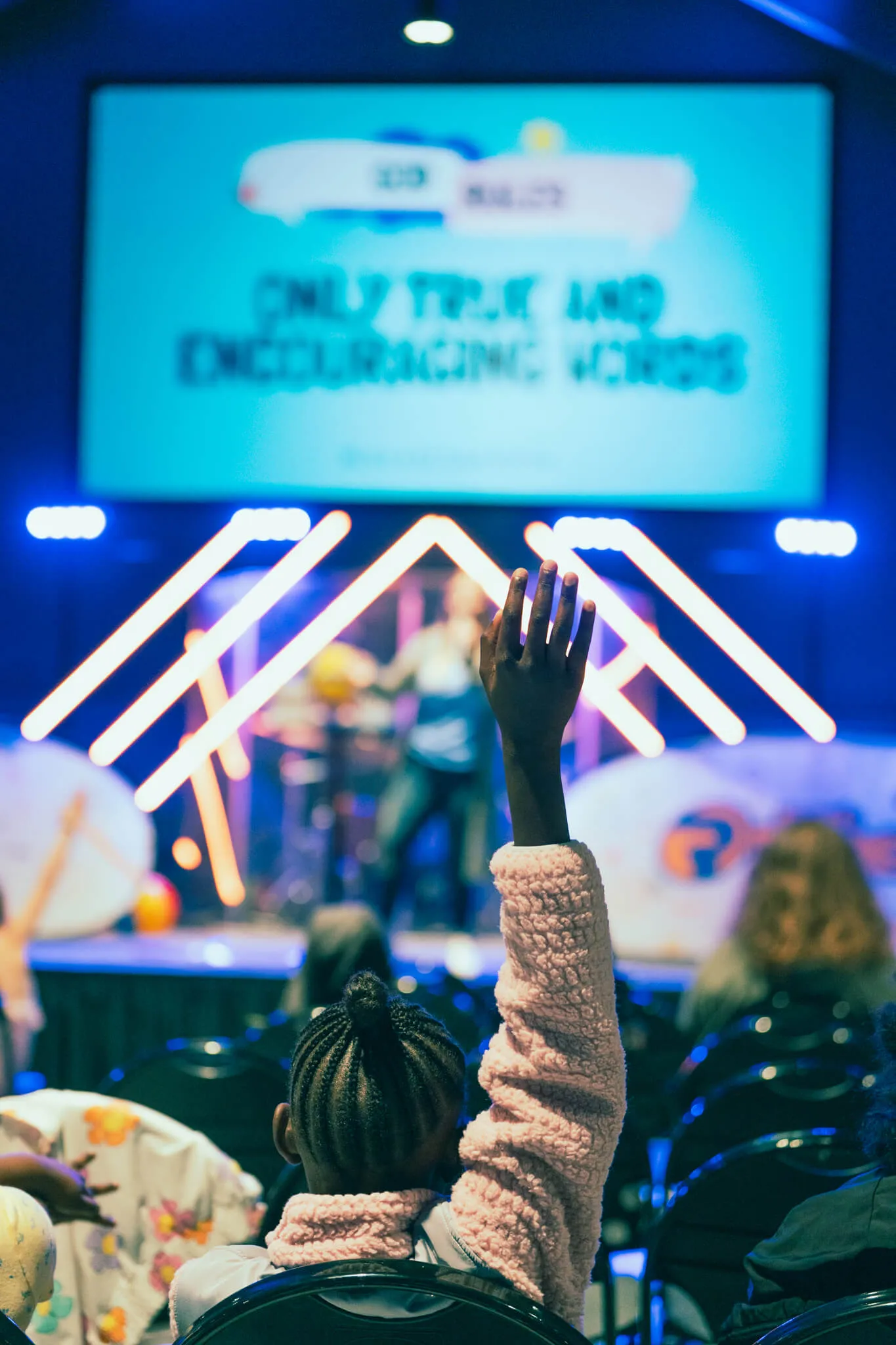 Children raising their hands in response to a sermon at Reach Church.
