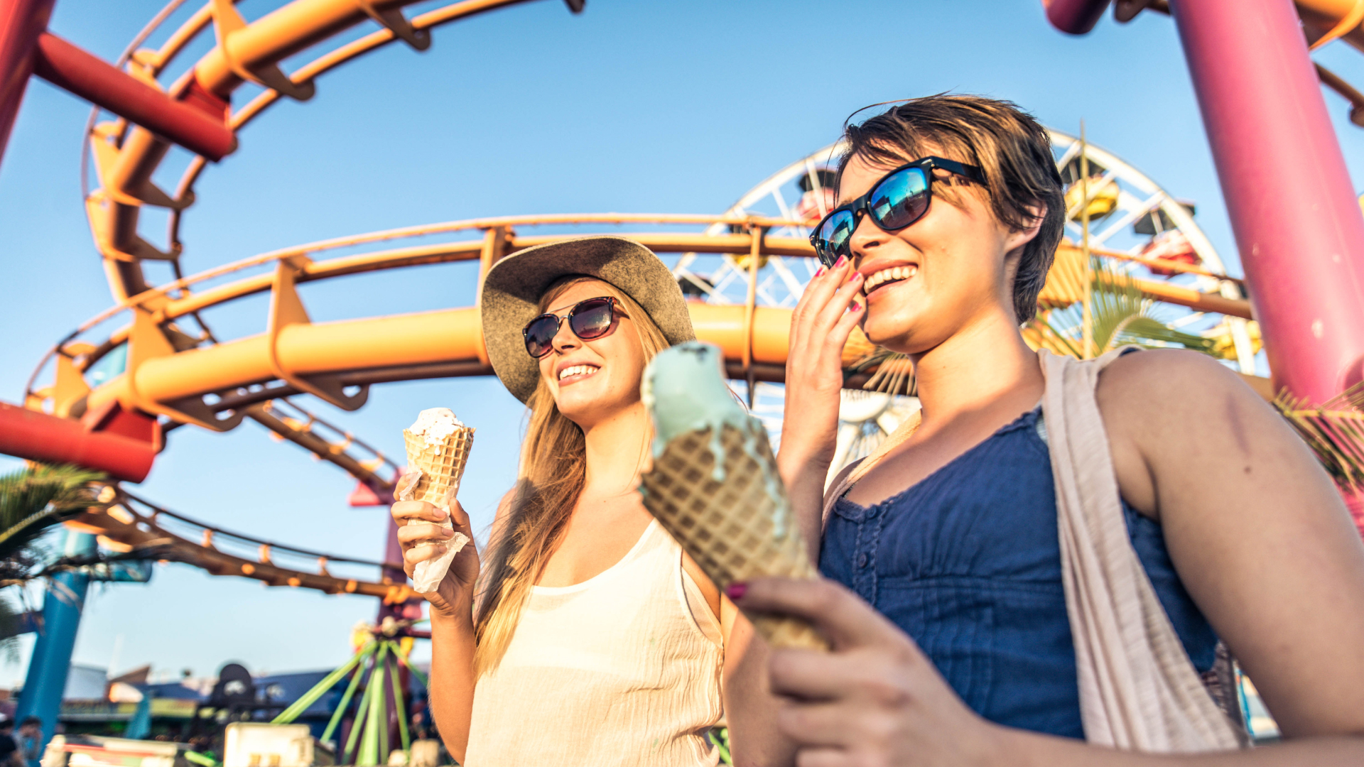 Two women enjoying ice cream at an amusement park