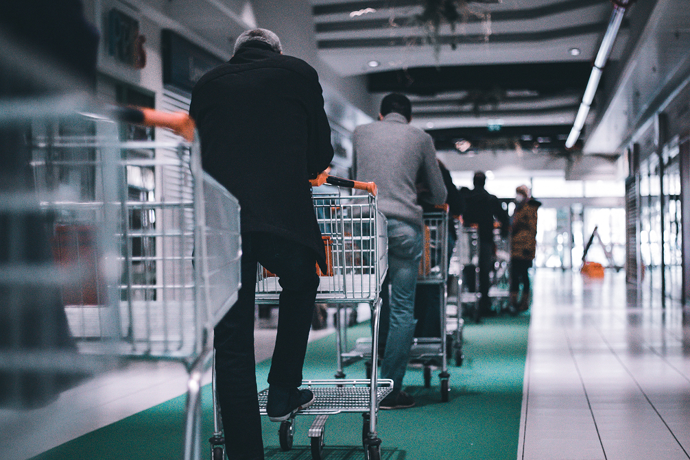 Customers with shopping carts walking through a retail store