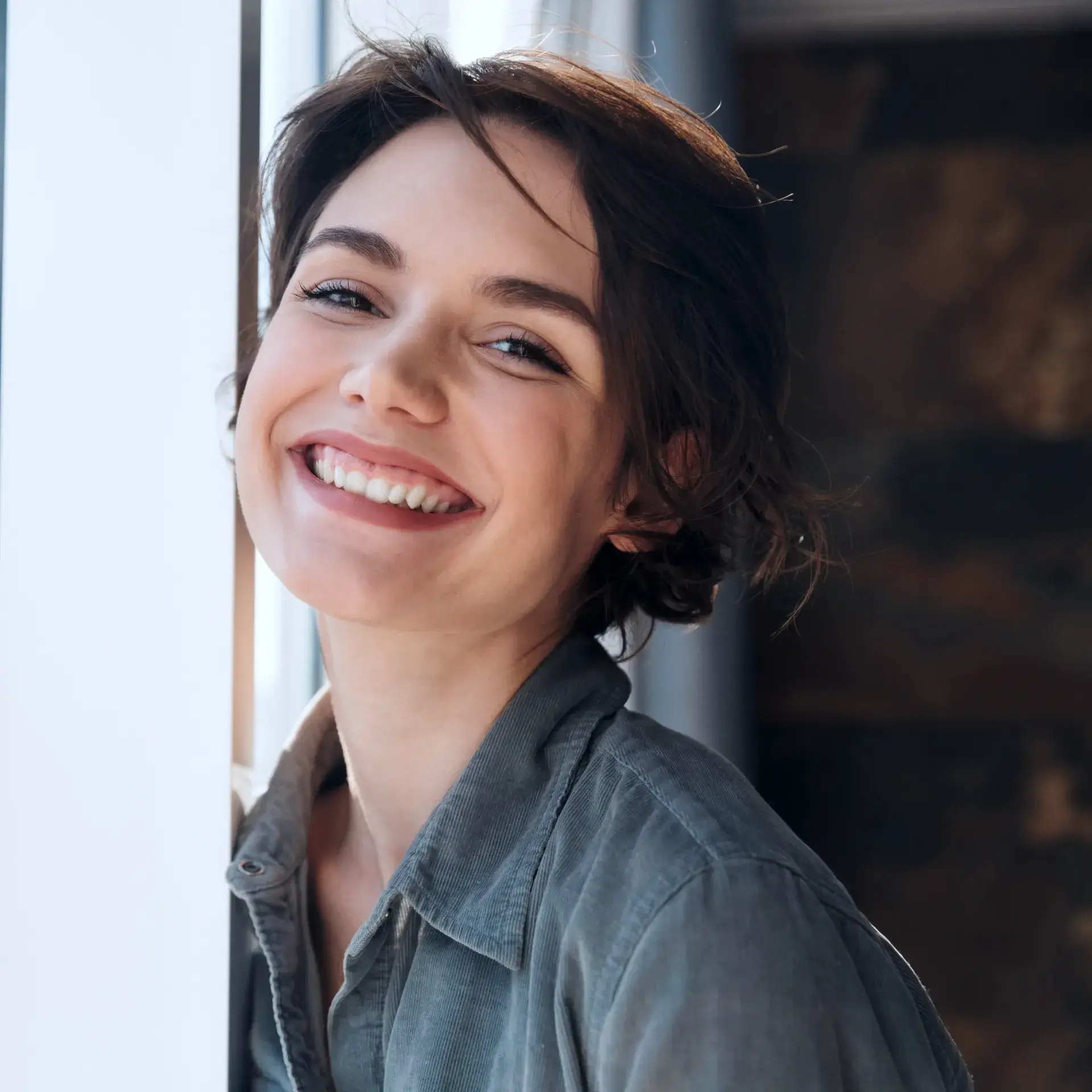 a woman smiling and leaning against a wall