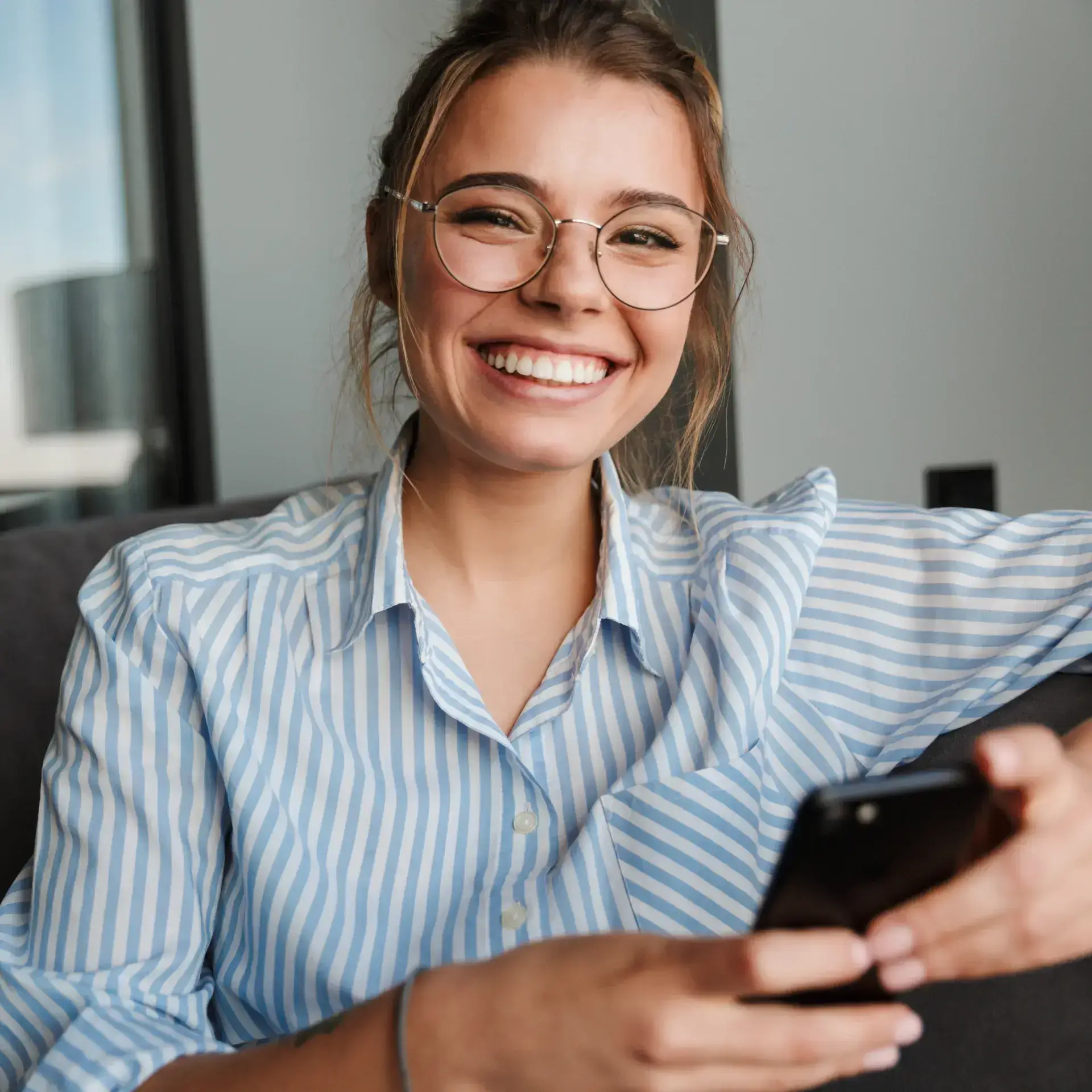 A woman wearing glasses is looking at her cell phone.