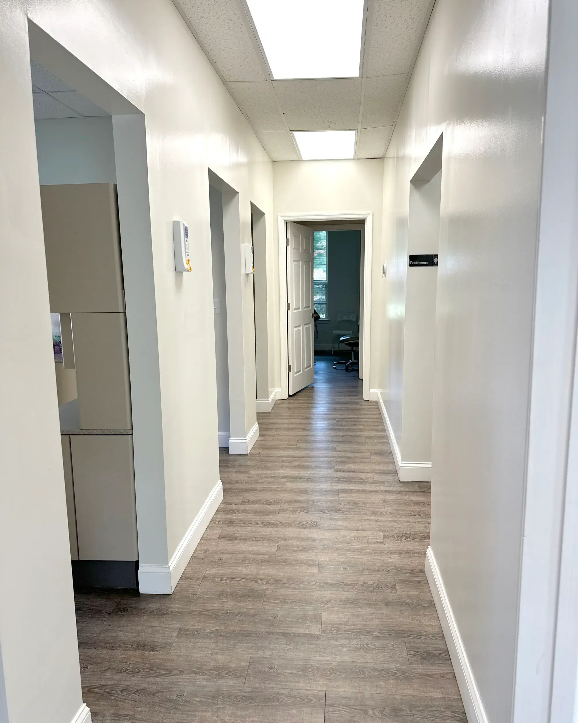 A clean hallway with wooden flooring, white walls, and several doorways leading to other rooms.