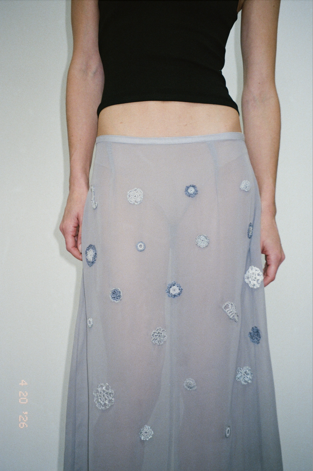 Model wearing BAO skirt, a sheer midi skirt with handmade sewn appliqués. 