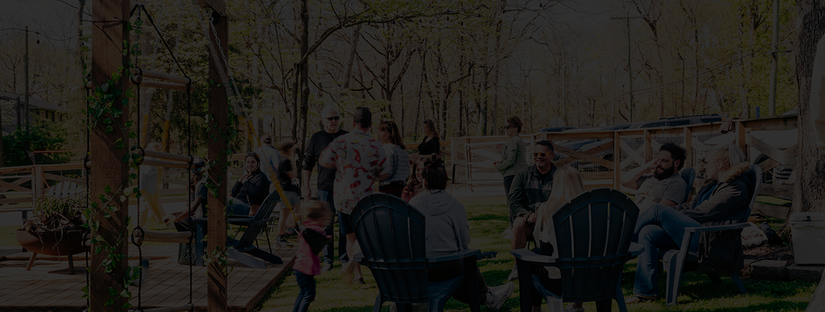 Top view of people toasting with drinks over a table with salad, avocados, rolls, and tomatoes; next to a group of four women smiling and chatting around a dinner table with a cake and flowers.