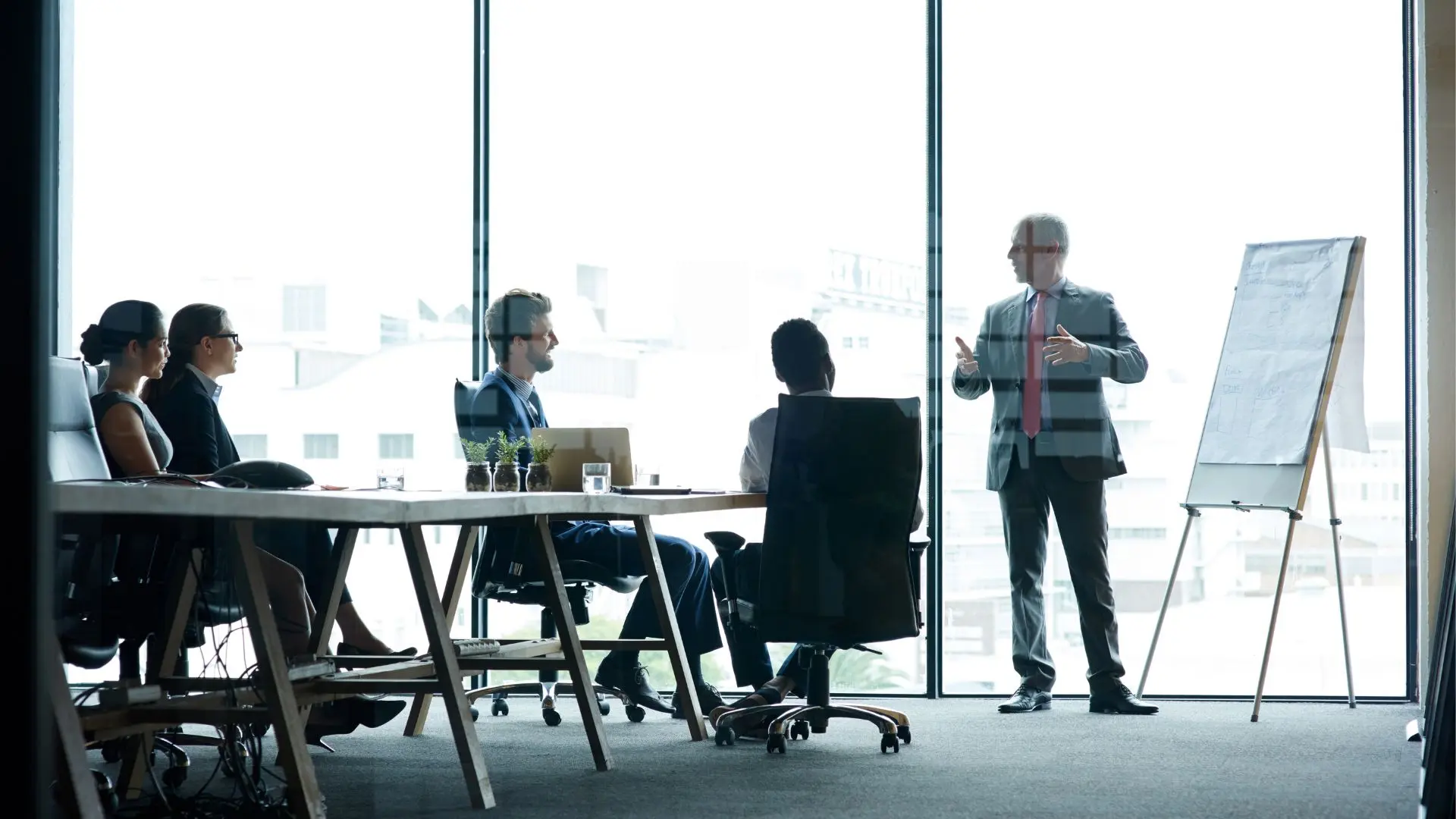 Vertriebsleitung präsentiert eine neue B2B-Vertriebsstrategie vor dem Team in einem modernen Konferenzraum.