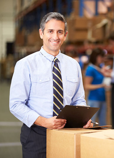 Man standing behind boxes whilst holding a clipboard 
