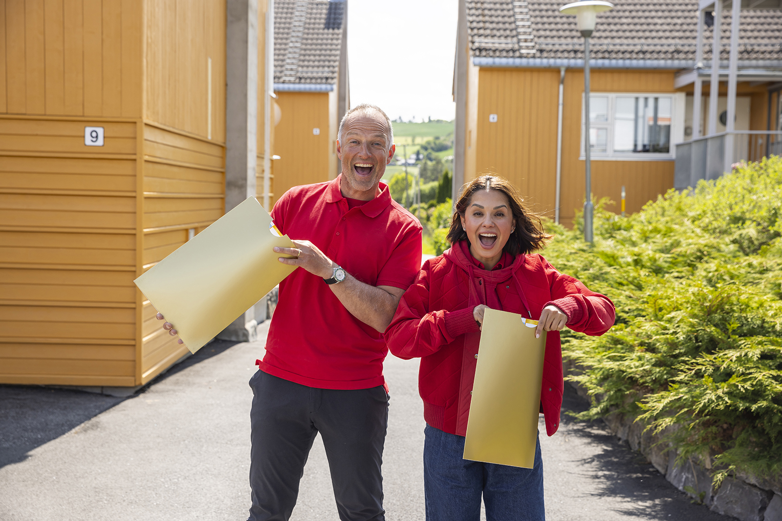 Tom og Jorun Stiansen smiler mens de holder noen store konvolutter. 