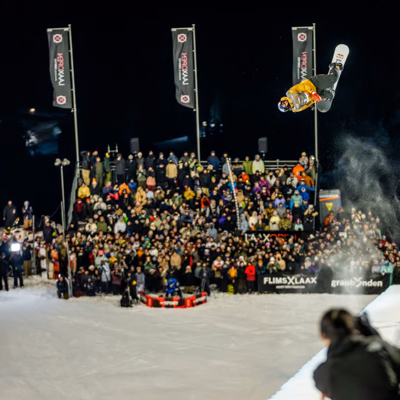 LAAX OPEN halfpipe finals Snowboarder jumping out the halfpipe with people watching below. 