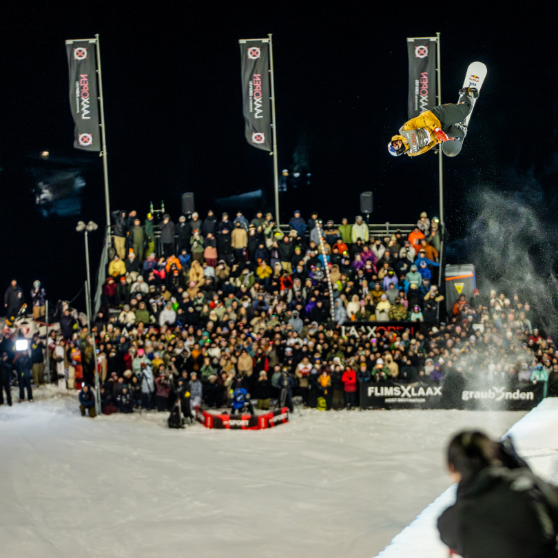 LAAX OPEN halfpipe finals: Snowboarders jumping out of the halfpipe while people watch from below. 