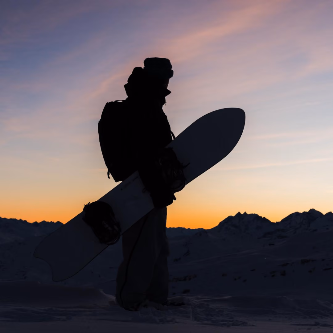 Silloutte of a snowboarder against the sunset in the alps