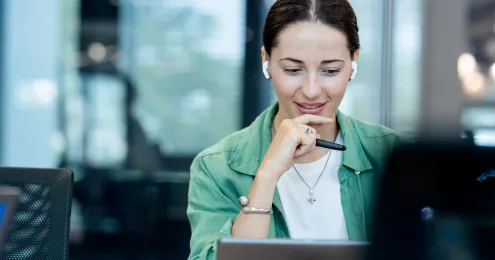 Person in einem modernen Büro, die konzentriert an einem Laptop arbeitet, mit einer Kaffeetasse im Vordergrund