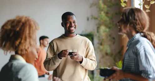 Eine Gruppe von Menschen steht in einem entspannten sozialen Umfeld, möglicherweise bei einer Kaffeepause oder einem informellen Treffen.