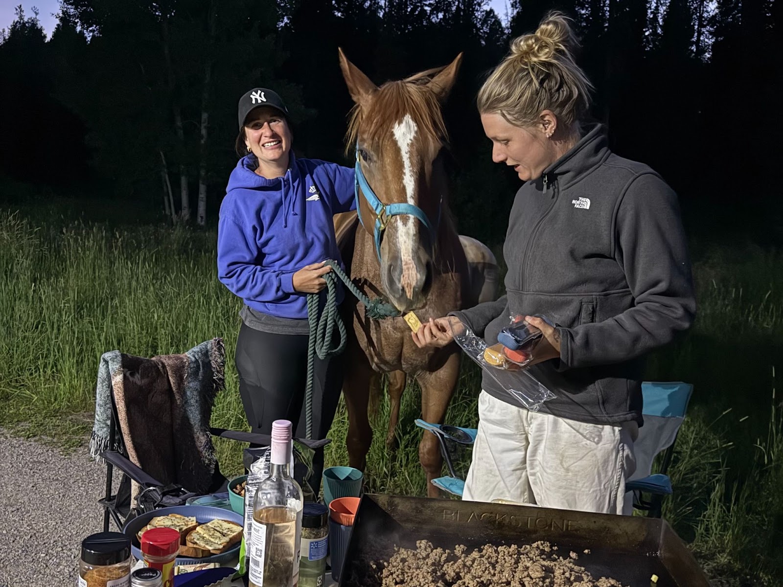 Cooking at camp, while a horse snacks on crackers