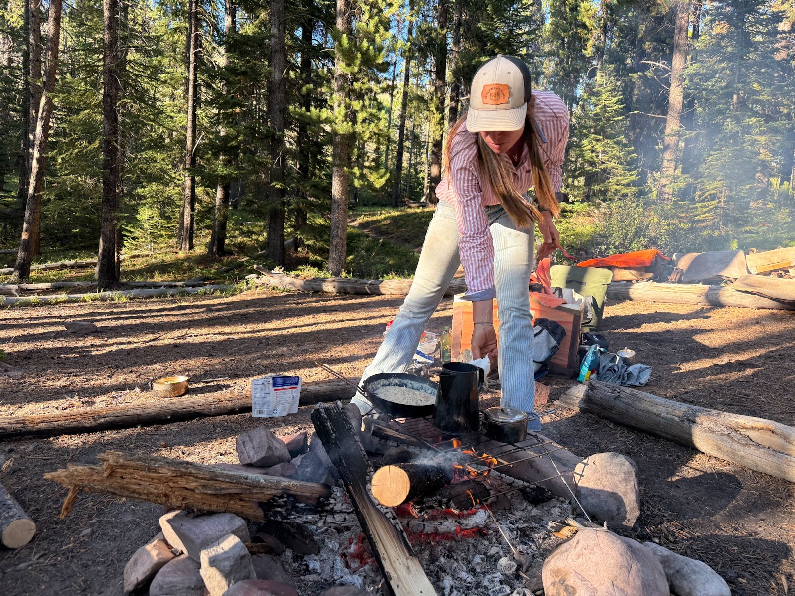Cowgirl cooking over the fire at camp in the forest