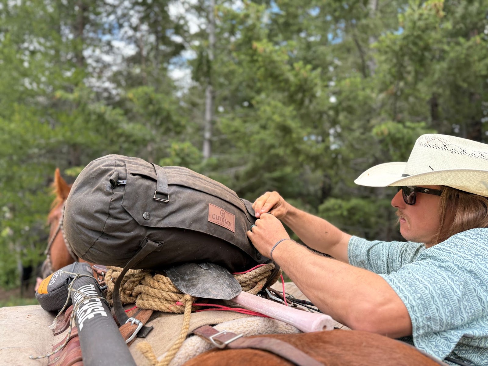 Cowboy packing luggage onto pack horse