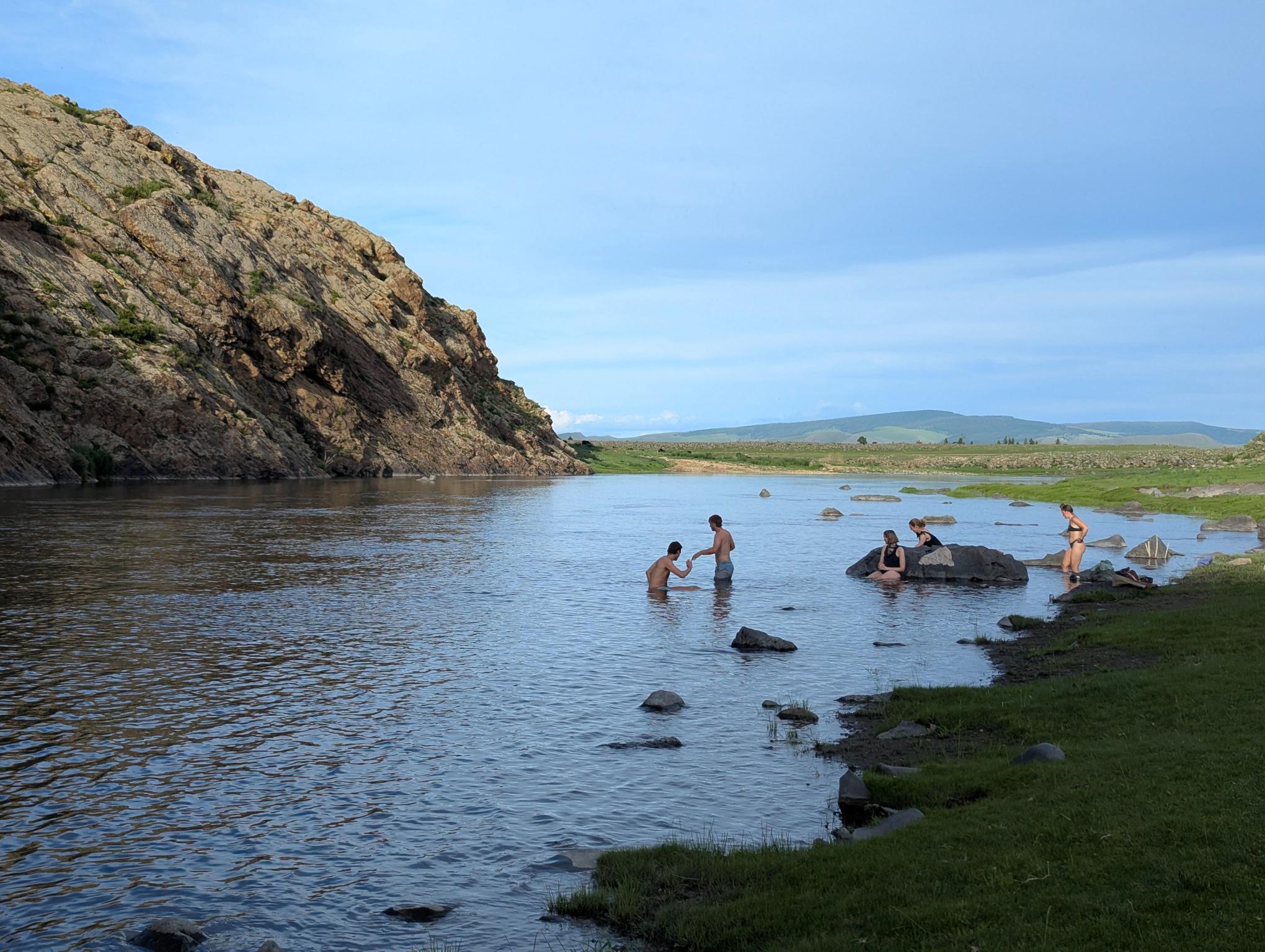 Group of people swimming in the river at sunset on a sunny day
