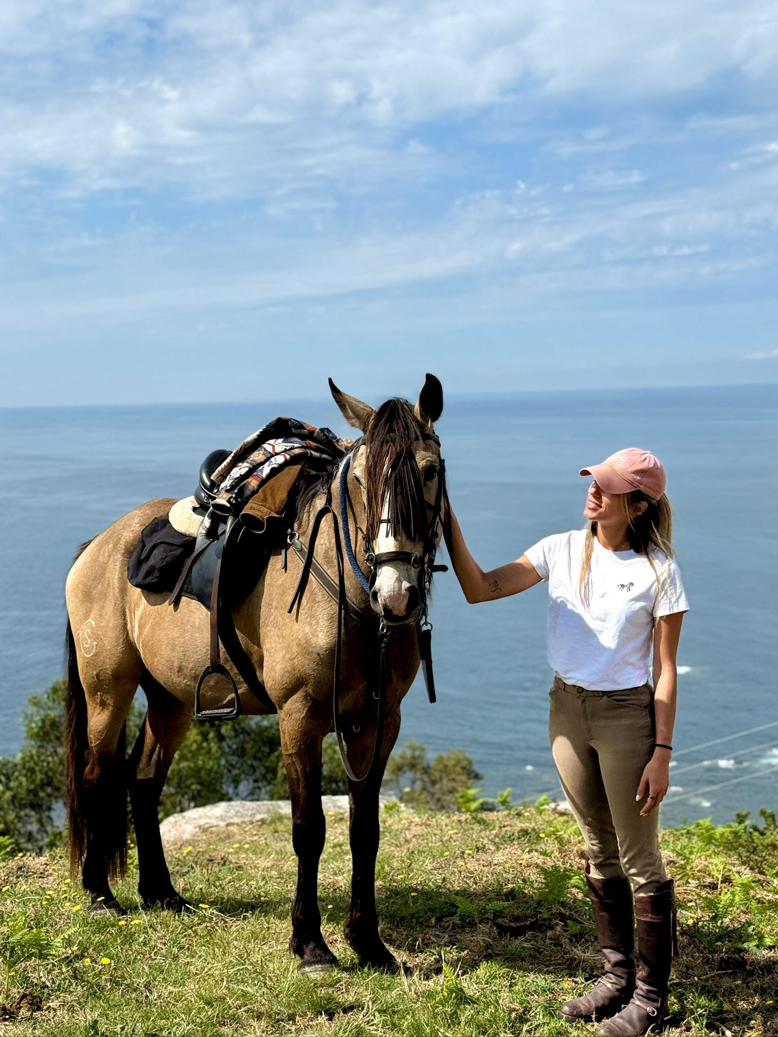 Rider and horse posing for a photo on top of a mountain by the ocean