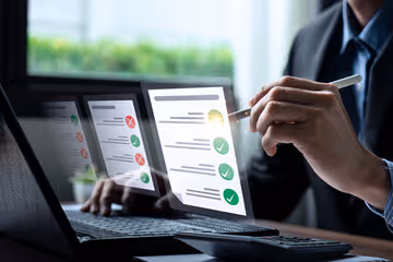 Équipe professionnelle en réunion de travail, analysant des graphiques sur ordinateur et documents papier, symbolisant la collaboration et l'analyse de données en entreprise.