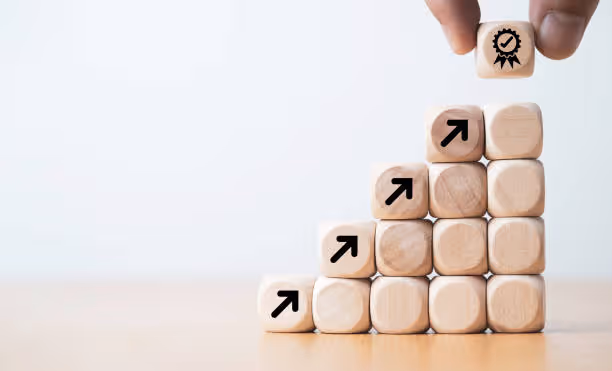 Blocs en bois empilés avec des flèches ascendantes représentant la croissance et la progression, avec un bloc final couronné d'une icône de réussite.