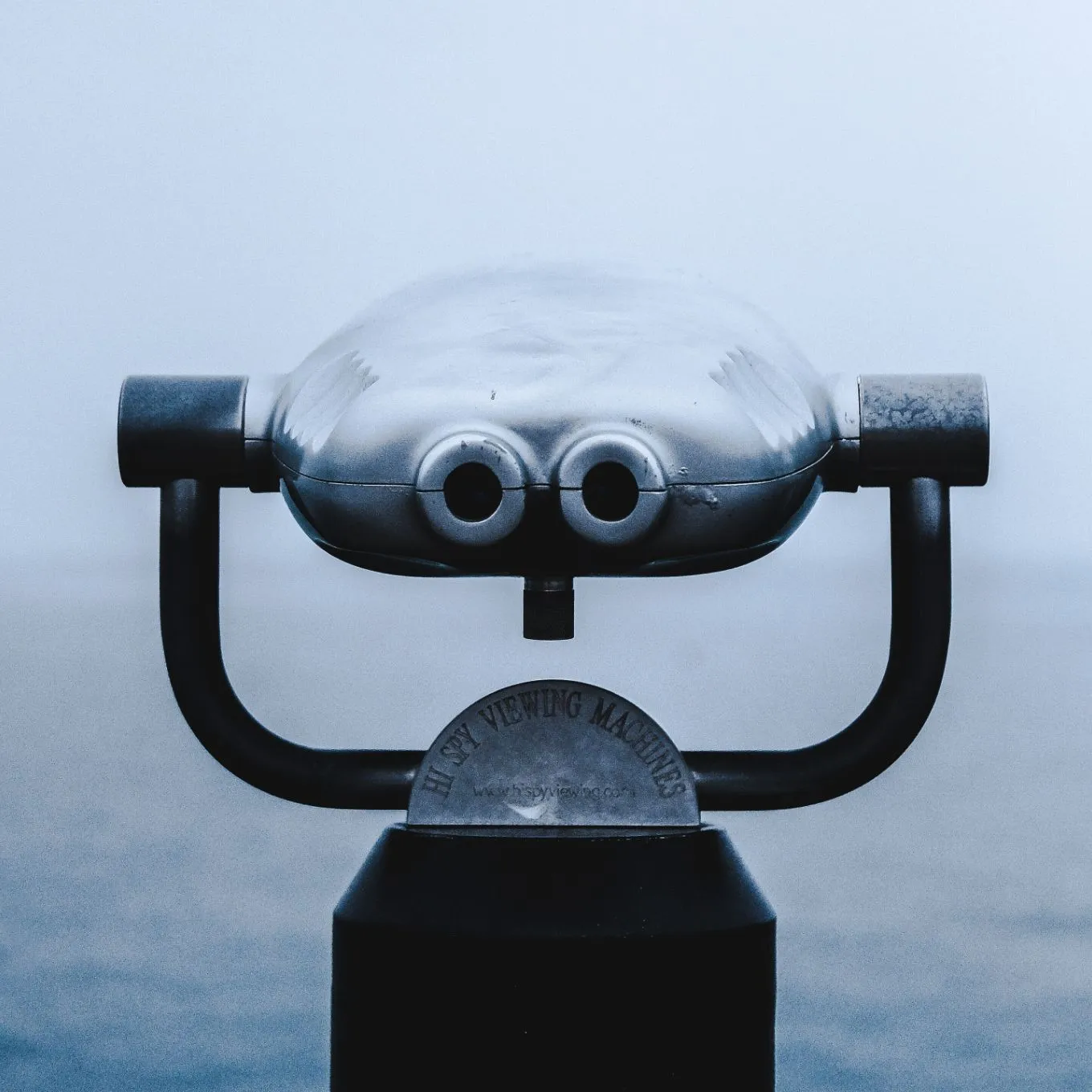 Silver coin-operated binocular viewer overlooking the sea on a foggy day.