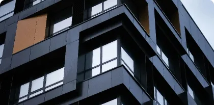 Modern building facade featuring large reflective windows and dark geometric panels.