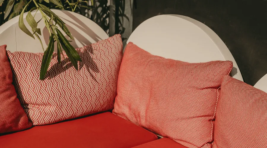 A photo of a seating area with red cushions and a plant draping over a white circular backing.